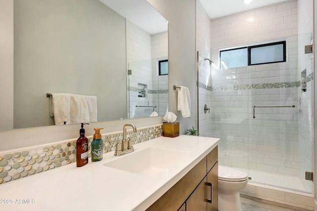 bathroom featuring vanity, a shower with door, and toilet