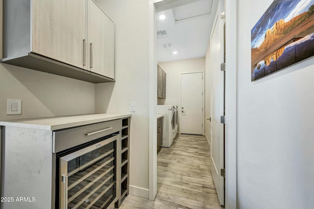 interior space featuring independent washer and dryer, beverage cooler, light brown cabinets, and light wood-type flooring