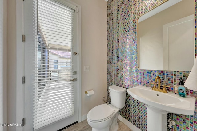 bathroom featuring toilet, sink, tasteful backsplash, wood-type flooring, and tile walls