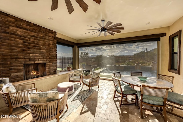 sunroom / solarium with an outdoor brick fireplace and ceiling fan