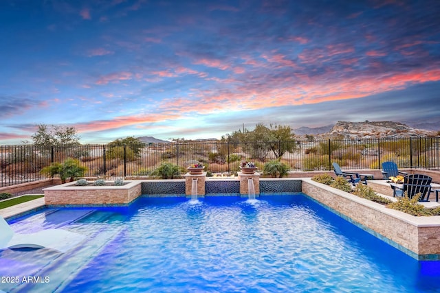 pool at dusk with a mountain view and pool water feature