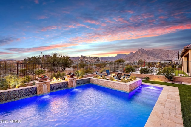 pool at dusk featuring pool water feature and a mountain view