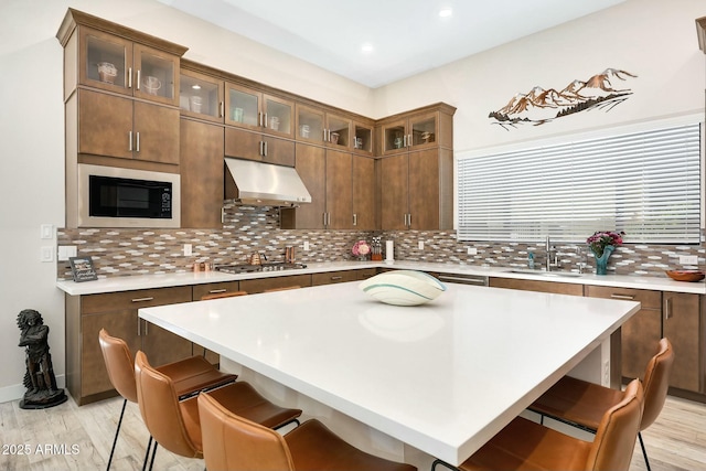 kitchen with built in microwave, a breakfast bar, sink, and decorative backsplash