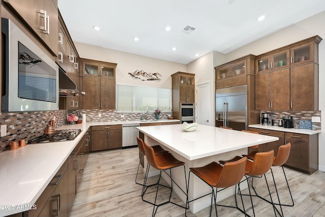 kitchen with appliances with stainless steel finishes, sink, a breakfast bar area, decorative backsplash, and a center island