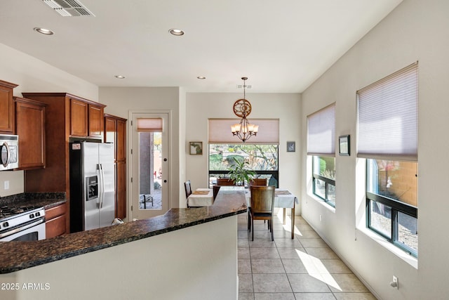 kitchen featuring visible vents, a chandelier, appliances with stainless steel finishes, decorative light fixtures, and brown cabinetry