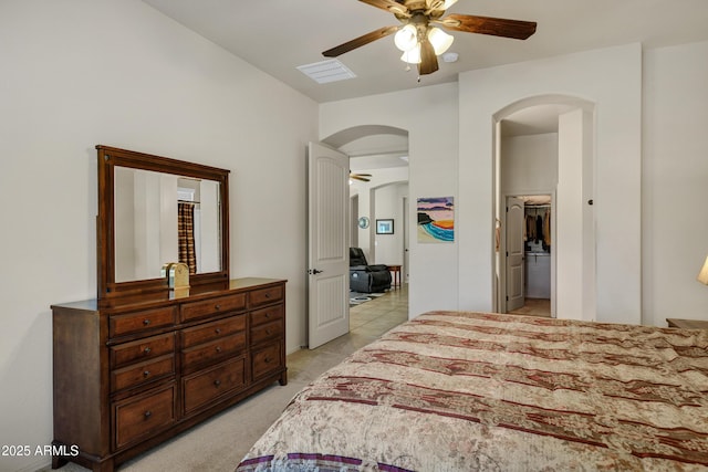 bedroom featuring visible vents, ceiling fan, light carpet, arched walkways, and a spacious closet
