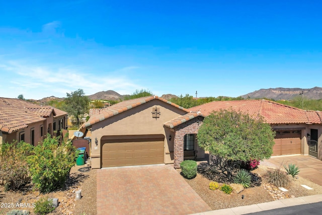 view of front of house featuring a tiled roof, stucco siding, a mountain view, and an attached garage
