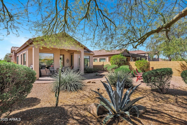 rear view of property featuring a tile roof, fence, and a patio area