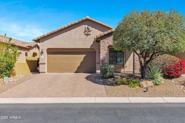 mediterranean / spanish home with stucco siding, a garage, a tiled roof, and decorative driveway