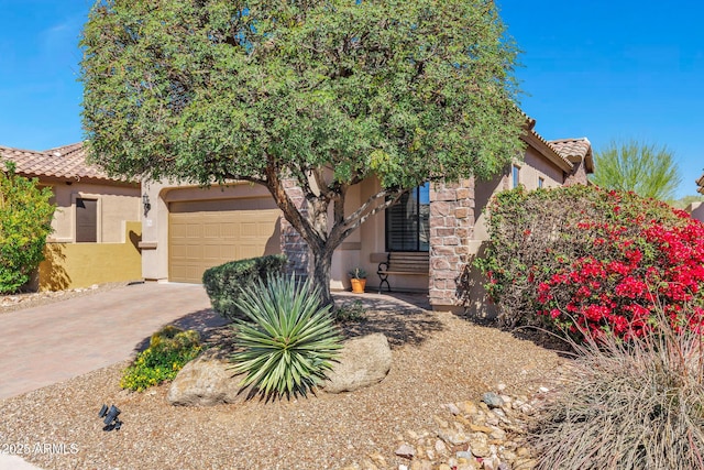 view of property hidden behind natural elements featuring stucco siding, a tile roof, and an attached garage