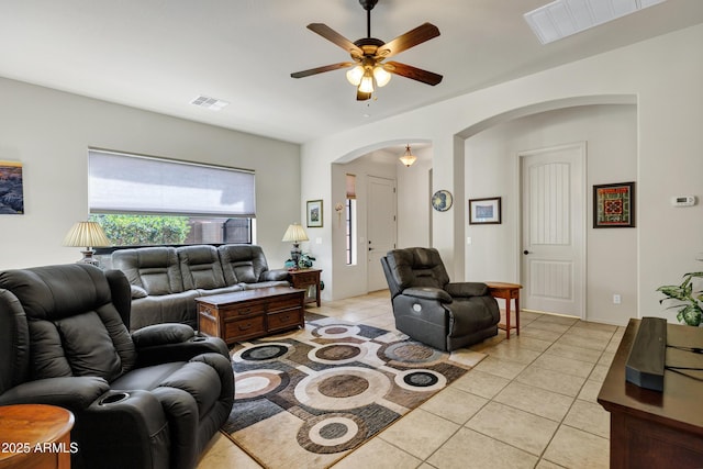 living room featuring lofted ceiling, light tile patterned floors, arched walkways, ceiling fan, and visible vents