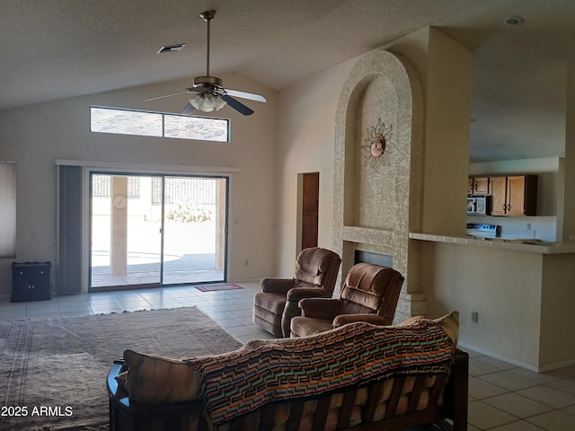 living room featuring ceiling fan, a large fireplace, high vaulted ceiling, and light tile patterned floors