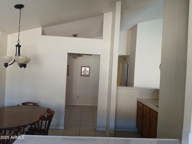 kitchen featuring vaulted ceiling, pendant lighting, a notable chandelier, and light tile patterned flooring