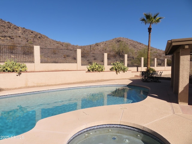 view of swimming pool with an in ground hot tub, a mountain view, and a patio