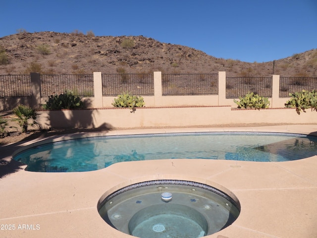 view of swimming pool with a mountain view and an outdoor hot tub