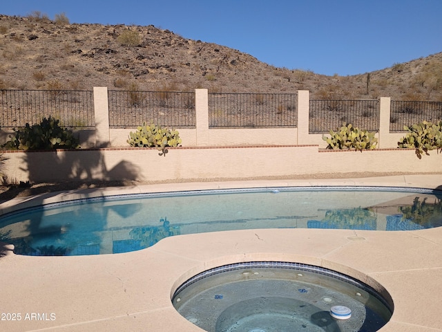 view of pool with a mountain view and an outdoor hot tub