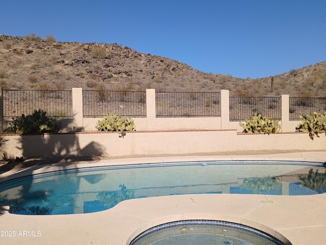 view of swimming pool with a mountain view and a jacuzzi