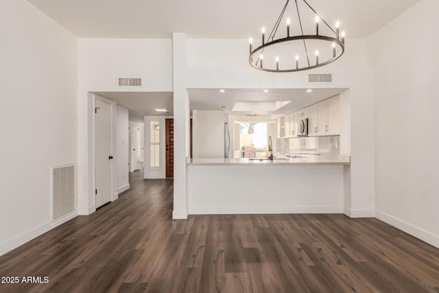 interior space featuring sink, refrigerator, dark hardwood / wood-style floors, white cabinets, and kitchen peninsula