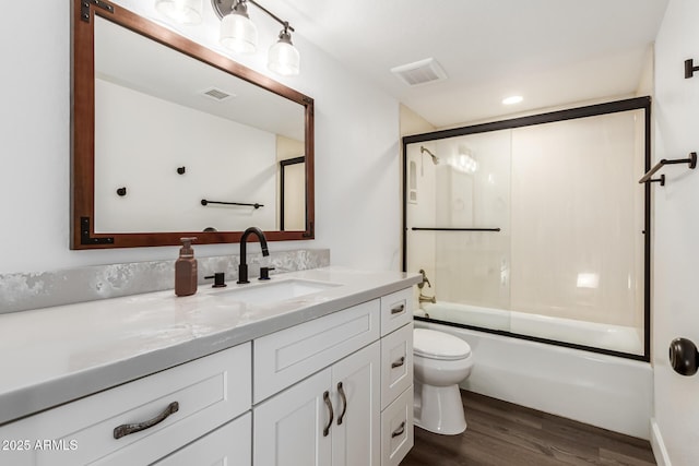 full bathroom with vanity, hardwood / wood-style floors, enclosed tub / shower combo, and toilet