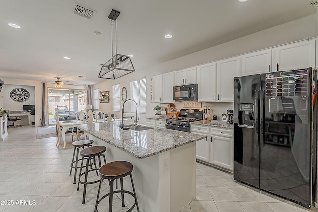 6566 E Via Arroyo Largo, Tucson, AZ 85756 - kitchen featuring black appliances, light tile patterned flooring, a breakfast bar, ceiling fan, and white cabinetry