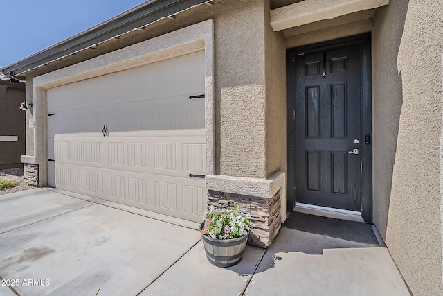 6566 E Via Arroyo Largo, Tucson, AZ 85756 - property entrance featuring stucco siding, stone siding, a garage, and concrete driveway