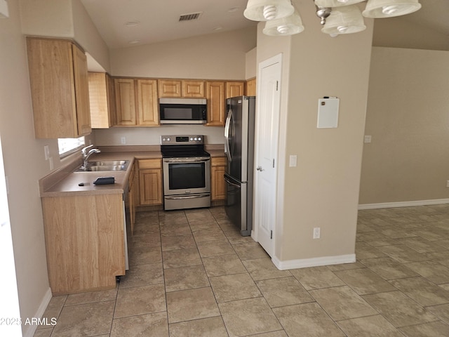 kitchen with lofted ceiling, appliances with stainless steel finishes, light brown cabinetry, and sink