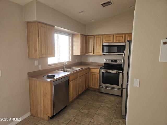 kitchen featuring sink, tile patterned flooring, stainless steel appliances, vaulted ceiling, and light brown cabinets