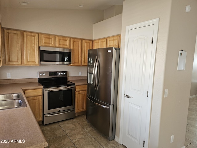 kitchen featuring stainless steel appliances, sink, vaulted ceiling, and light brown cabinets