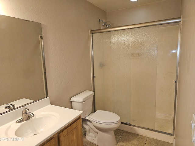 bathroom featuring tile patterned flooring, vanity, a shower with door, and toilet