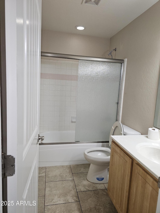 full bathroom featuring vanity, tile patterned flooring, combined bath / shower with glass door, and toilet