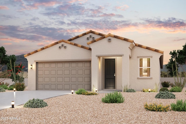 mediterranean / spanish-style house with a tiled roof, an attached garage, driveway, and stucco siding