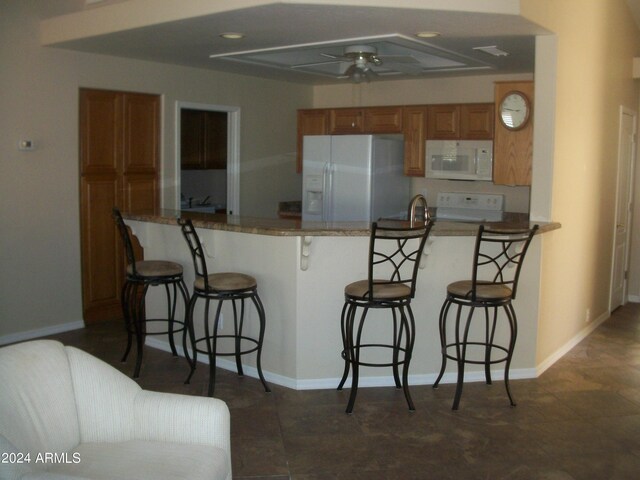 5830 E Mckellips Rd Unit 62, Mesa, AZ 85215 - kitchen with washing machine and clothes dryer, brown cabinets, a kitchen breakfast bar, and white fridge with ice dispenser