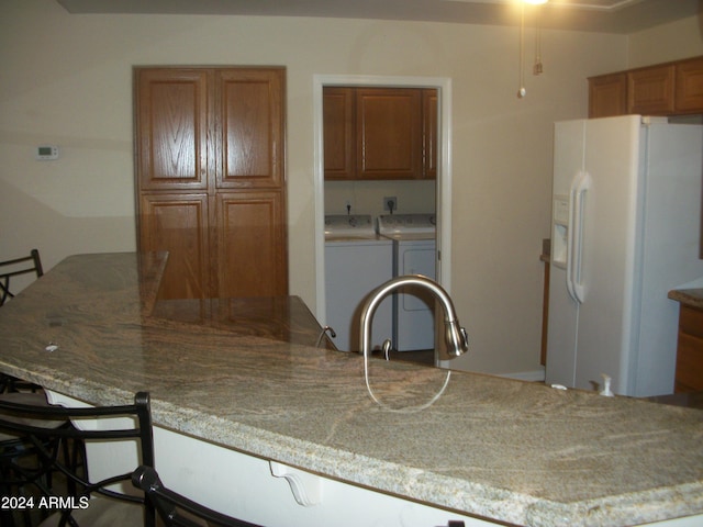 5830 E Mckellips Rd Unit 62, Mesa, AZ 85215 - kitchen featuring brown cabinetry, independent washer and dryer, white fridge with ice dispenser, and a kitchen breakfast bar