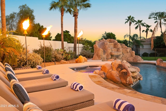 pool at dusk featuring an in ground hot tub