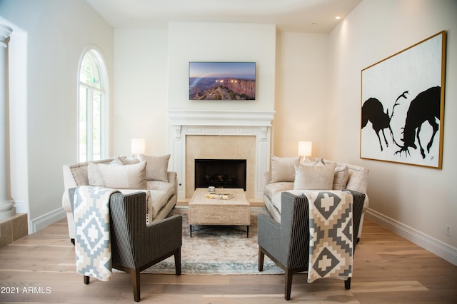 living area featuring a fireplace, light hardwood / wood-style floors, and ornate columns