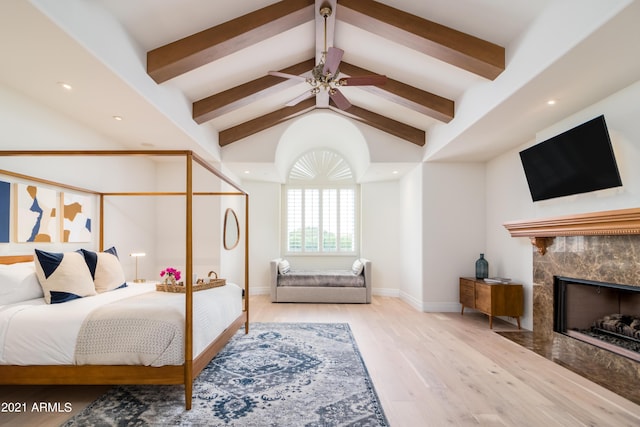 bedroom featuring ceiling fan, high vaulted ceiling, a high end fireplace, beamed ceiling, and light wood-type flooring