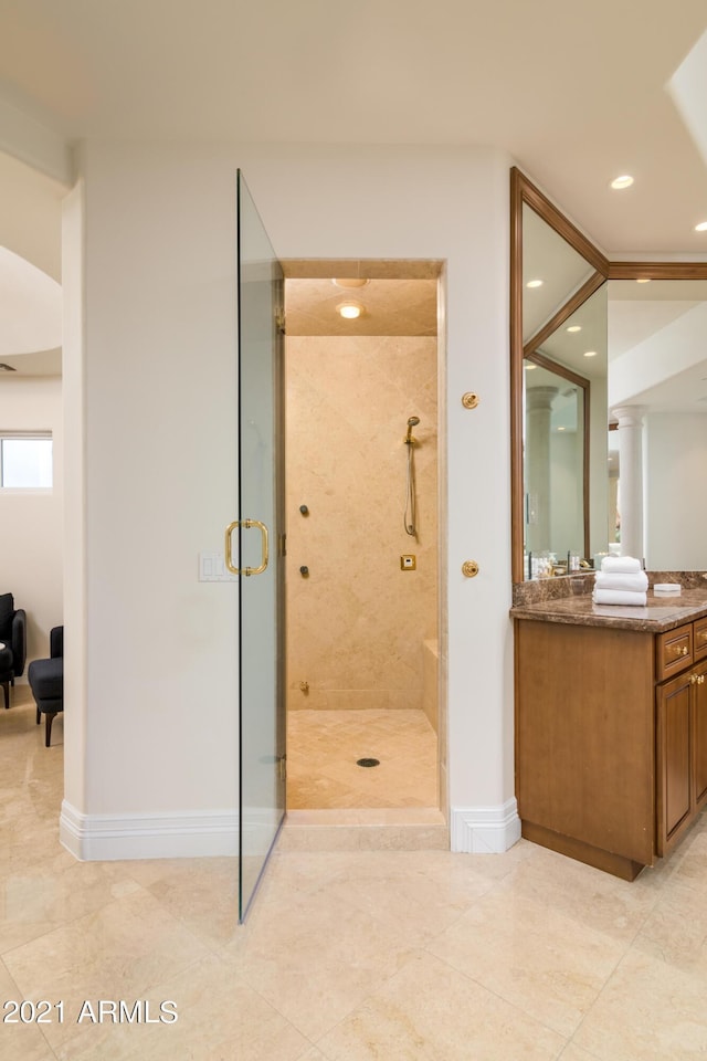 bathroom with a shower with door, vanity, and decorative columns