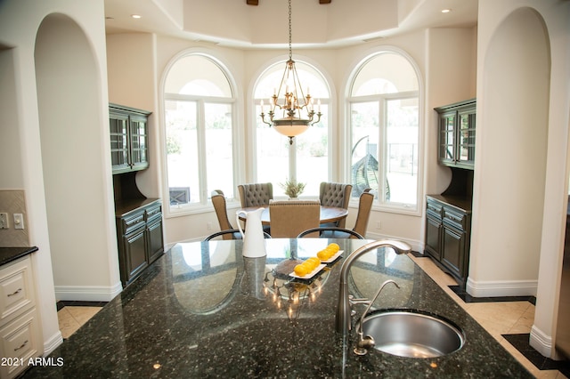 kitchen with dark stone counters, sink, hanging light fixtures, and light tile patterned floors