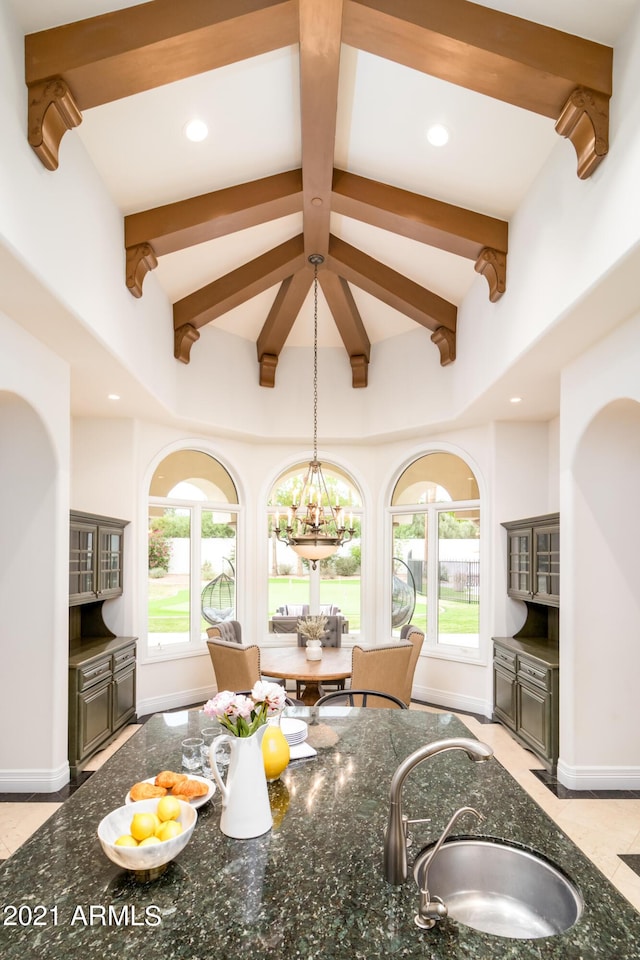 kitchen featuring hanging light fixtures, sink, a notable chandelier, and dark stone counters