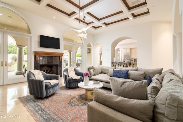 living room with french doors, coffered ceiling, beam ceiling, a towering ceiling, and a premium fireplace