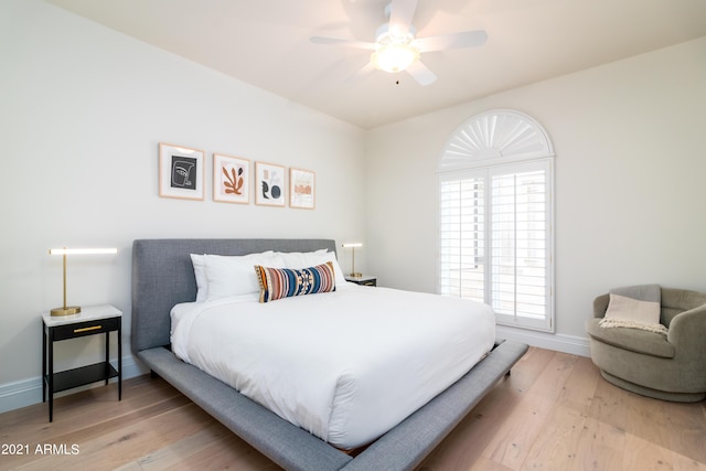 bedroom featuring hardwood / wood-style flooring, ceiling fan, and multiple windows