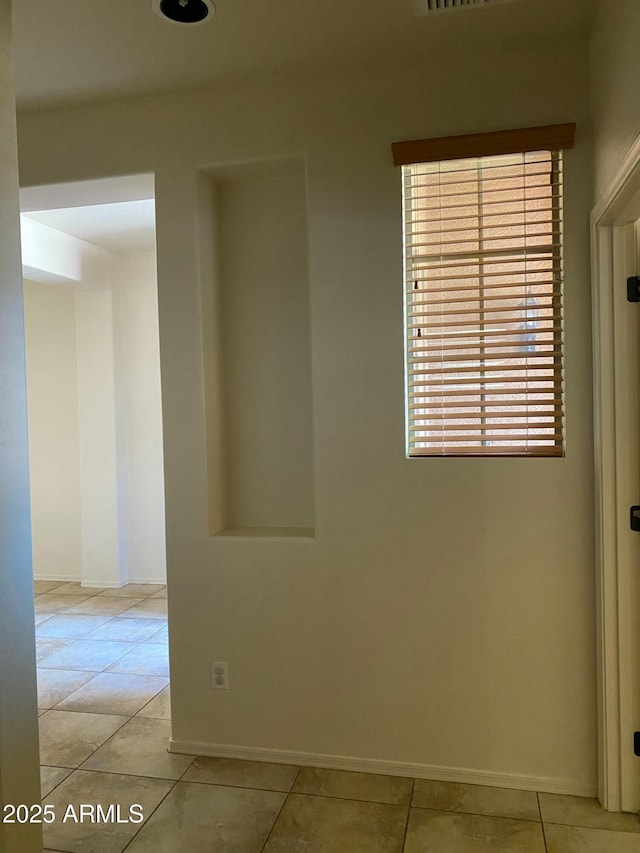 empty room with light tile patterned flooring and baseboards