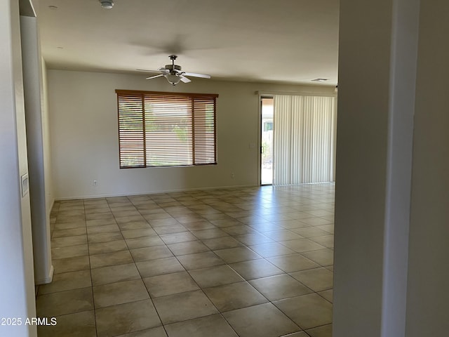 empty room with baseboards, a ceiling fan, and tile patterned floors