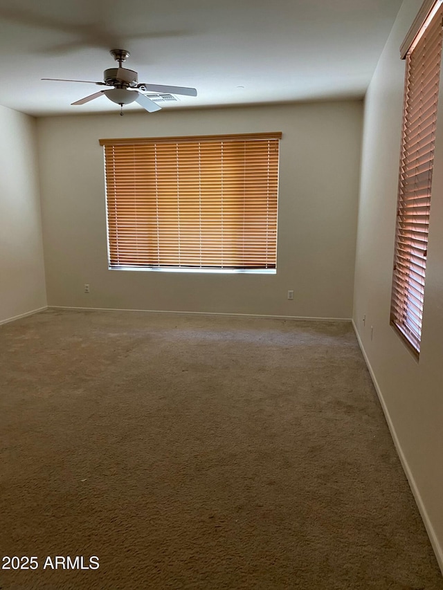 carpeted empty room featuring ceiling fan and baseboards