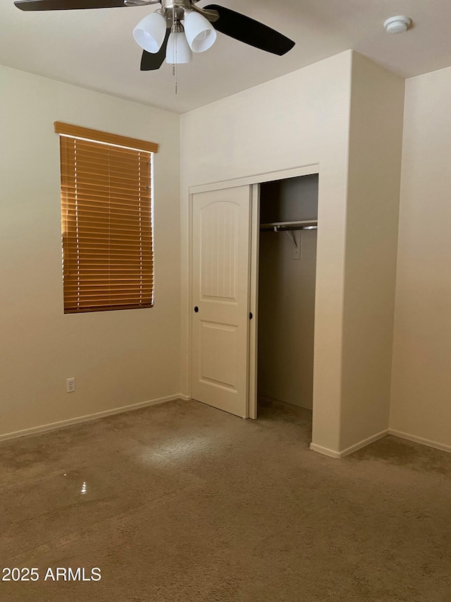 unfurnished bedroom with carpet floors, a closet, baseboards, and a ceiling fan