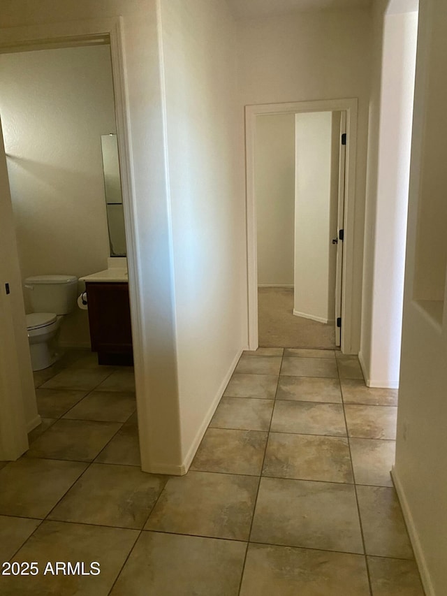 hallway with light tile patterned flooring and baseboards