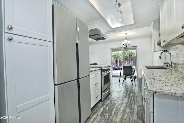 kitchen featuring wall chimney range hood, backsplash, track lighting, appliances with stainless steel finishes, and sink