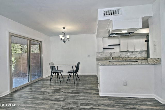 kitchen featuring dark wood-type flooring, decorative backsplash, an inviting chandelier, and white cabinets