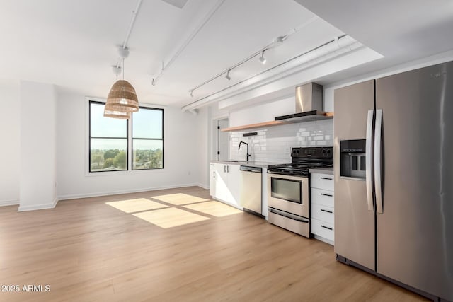 kitchen featuring backsplash, light hardwood / wood-style floors, hanging light fixtures, stainless steel appliances, and wall chimney exhaust hood