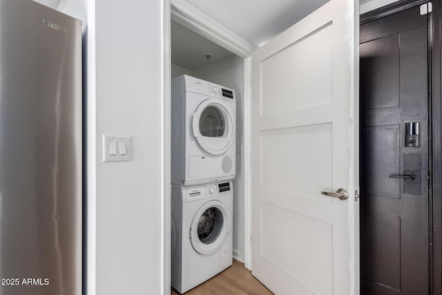 washroom featuring stacked washer and dryer and light hardwood / wood-style floors